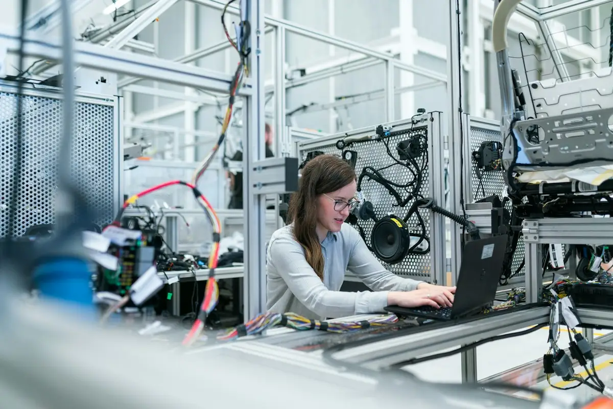 Técnica trabajando con una notebook junto a una máquina industrial